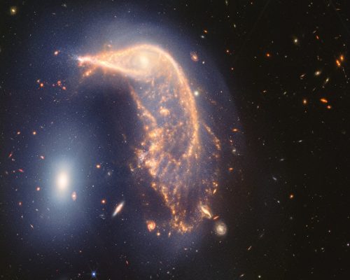 The distorted spiral galaxy at the centre, the Penguin, and the compact elliptical galaxy at the left, the Egg, are locked in an active embrace. A new near- and mid-infrared image from the James Webb Space Telescope, taken to mark its second year of science, shows that their interaction is marked by a faint upside-down U-shaped blue glow. (Photo: NASA, ESA, CSA, STScI)